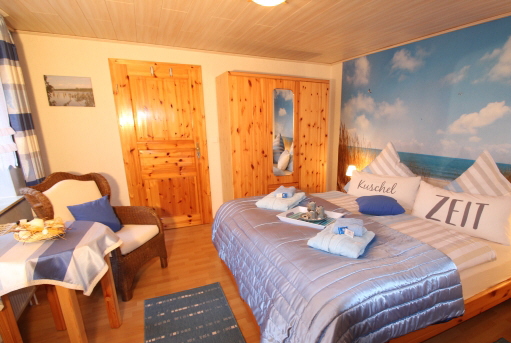 Schlafzimmer blau-weiß der Ferienwohnung Lüthje in Hochdonn in Dithmarschen am Nord-Ostsee-Kanal mit Doppelbett, Nachttischlampen, Nachttischen, Radiowecker, Herrendiener